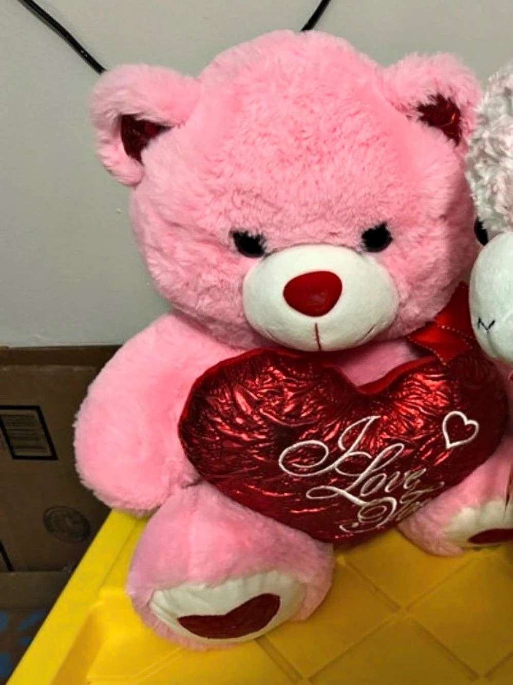 Pink teddy bear with red heart pillow that says 'I Love You'